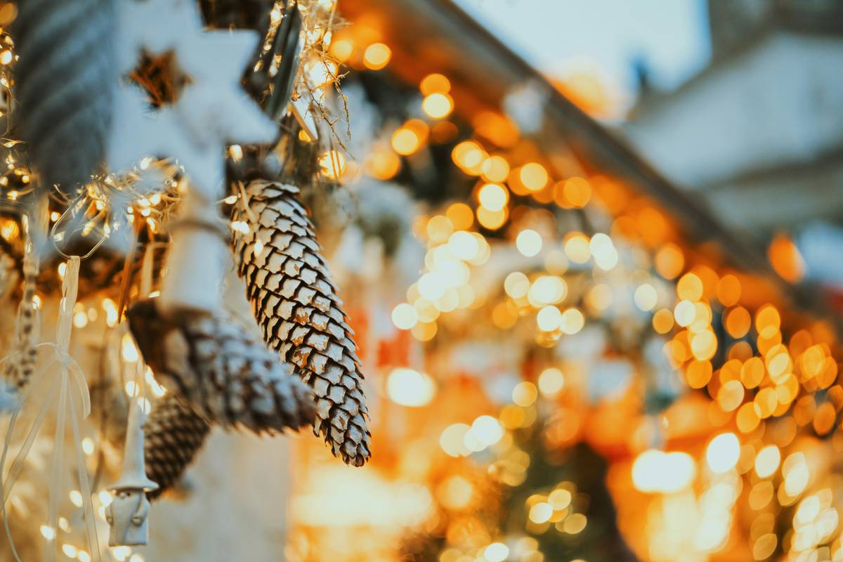 Close-up of metallic spiral tree cones hanging on a flocked Christmas tree, catching soft ambient light to show their helical reflectivity