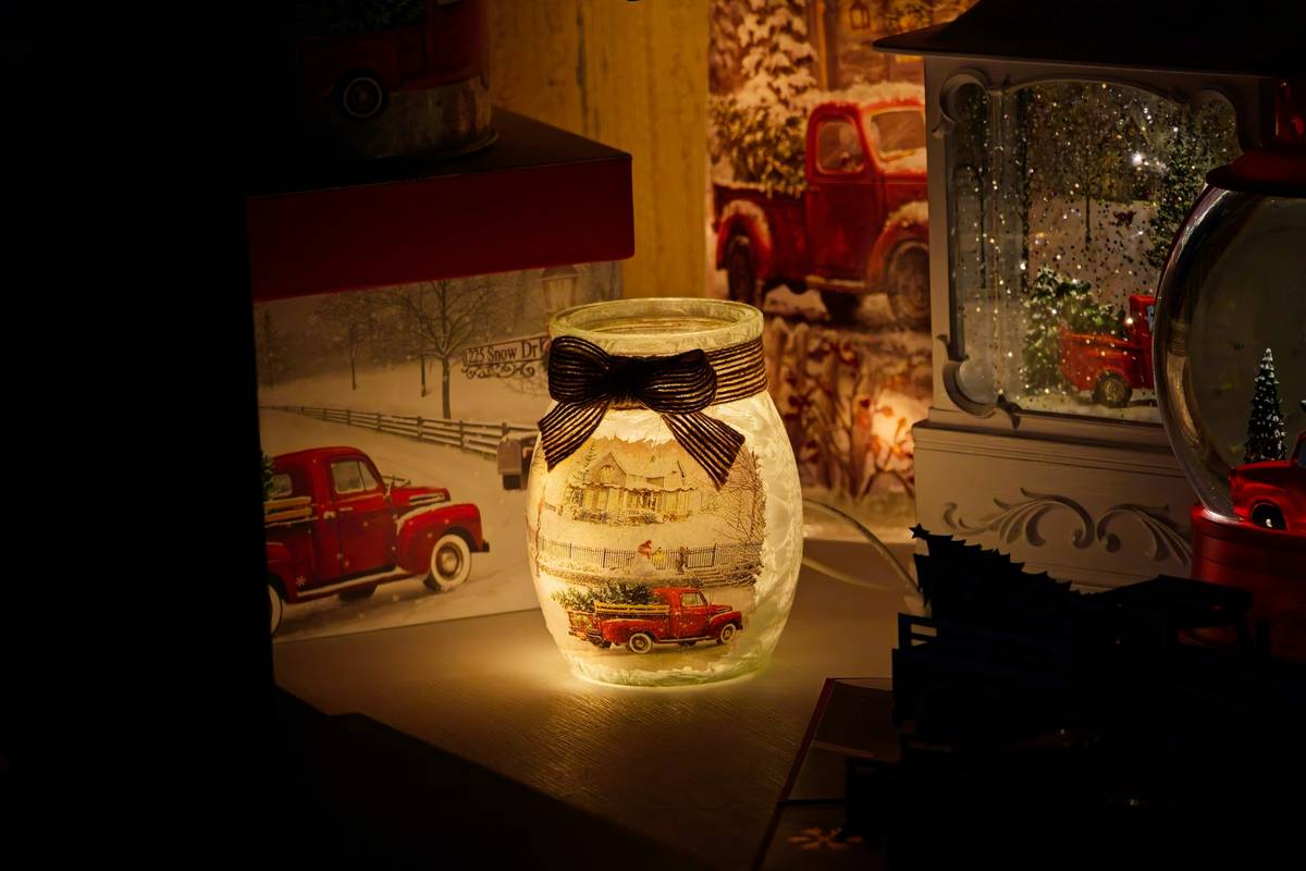 Infographic showing safe vs unsafe mason jar luminary setups: left side shows LED light inside clean jar with pine sprig; right side shows real candle inside sealed painted jar with warning symbol