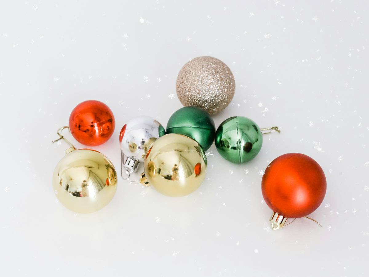 Side-by-side photo showing a shattered glass ornament next to an intact shatterproof ball after being dropped on hardwood floor